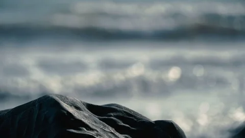 Beautiful view of slow motion out of focus waves behind smooth rocks on beach Stock Footage 119533214