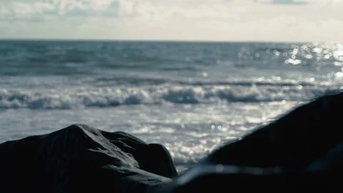 Beautiful view of slow motion out of focus waves behind smooth rocks on beach v3 Stock Footage 119533224