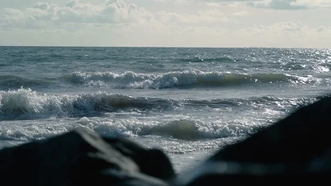Beautiful view of slow motion waves behind out of focus rocks on beach v2 Stock Footage 119533492