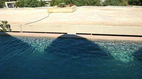 Beautiful view of swimming pool with rippling water beside sunny resort terrace Stock Footage 343879020