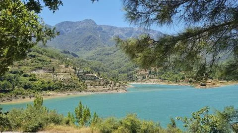 Beautiful view through the tree branches to the mountains and turquoise lake. Stock Photos