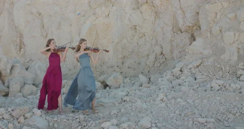 Beautiful view of two elegant ladies in dresses play violin at cliff background Vidéo 136074572