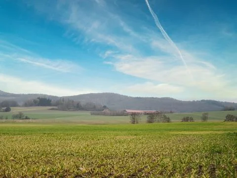 Beautiful view of a valley with wide fields and mountains and a farm in the.. Stock-Fotos