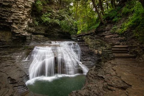 A beautiful view of the waterfall streaming down from the rocky cliff into th Foto stock