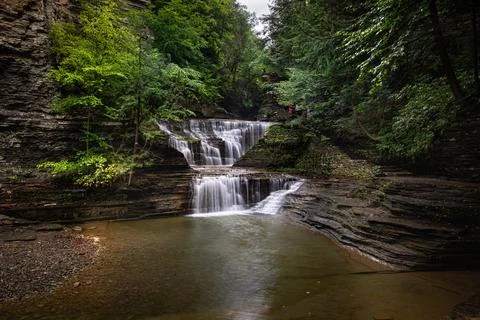 A beautiful view of the waterfall streaming down from the rocky cliff into th Stock-Fotos