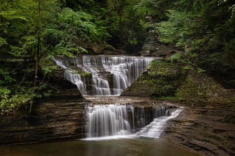 A beautiful view of the waterfall streaming down from the rocky cliff into th Foto stock