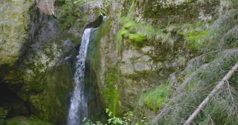 Beautiful waterfall cascading down rocky cliff surrounded by lush greenery in Stockbeeldmateriaal 314111838