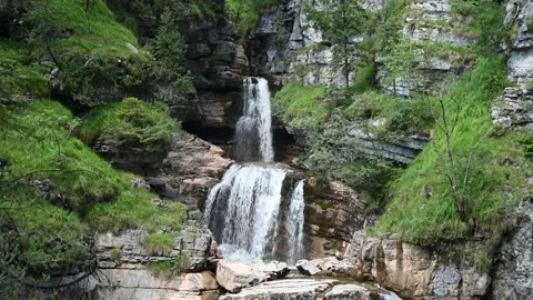 A beautiful waterfall cascading over rocks in the mountains (cloudy sky) Video stock 219418727