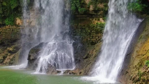 Beautiful waterfall cascading over rocks into a green pool Stock Footage 341932673