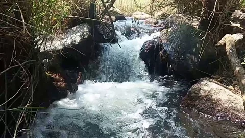 A beautiful waterfall Flowing, passing down between two small rocks in sunlight. Stock Footage 95722800