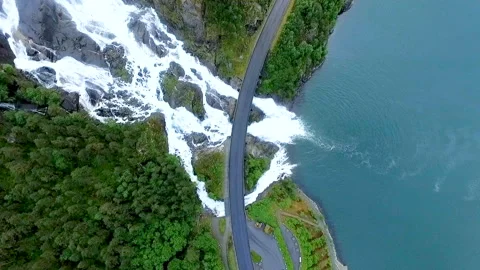 A beautiful waterfall flows from a steep mountain and flows into a large river Stock Footage 150648911