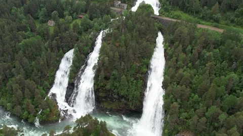 A beautiful waterfall flows from a steep mountain and flows into a large river. Stock Footage 245634683