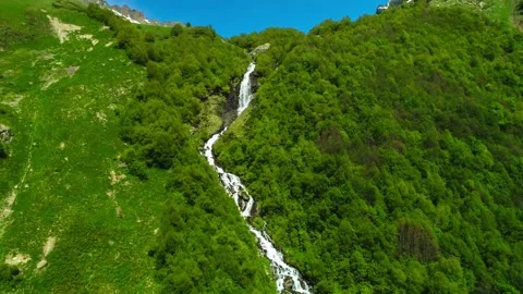 A beautiful waterfall on a mountain slope in the middle of a green forest. Stock Footage 157237003