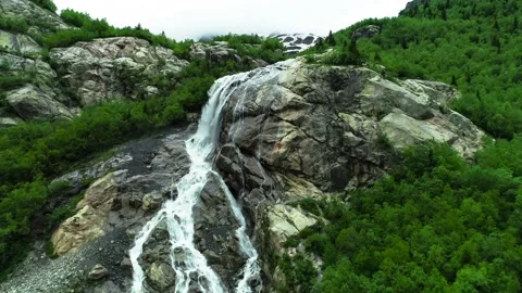 A beautiful waterfall on a mountain slope in the middle of a green forest. 库存影片 157239940