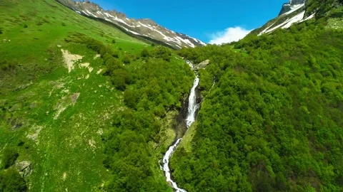 A beautiful waterfall on a mountain slope in the middle of a green forest. Stock Footage 157239948