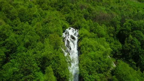 A beautiful waterfall on a mountain slope in the middle of a green forest. Stock Footage 157240063