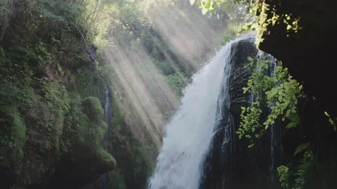 Beautiful waterfall with sun rays in a lush green forest in Oita Stock Footage 336772130