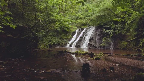 A Beautiful Waterfall Surrounded by Green Tree's and Mossy Rocks Stock Footage 113417647