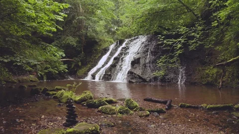 A Beautiful Waterfall Surrounded by Green Tree's and Mossy Rocks Stock Footage 113417680