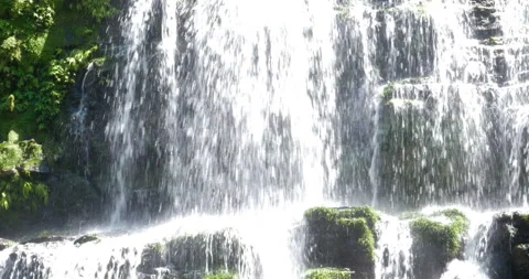 Beautiful Waterfalls Cascading Down Over Rock Face Under Green Jungle Canopy Stock Footage 138332934