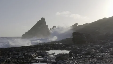 Beautiful waves splashing over rock formations in slow motion during sunset Stock Footage 74907917