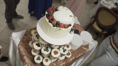 Beautiful wedding cake with a heart on top decorated with fresh berries at the Stock Footage 306144635