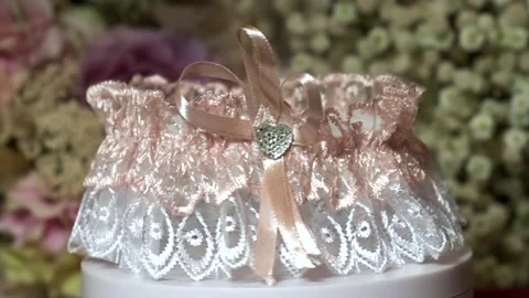 Beautiful wedding garter revolve on the background of the wedding bouquet. Stock Footage 153523048