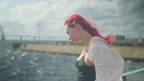 Beautiful well dressed red-haired girl on the seacoast in a sunny day Stock Footage 160985119