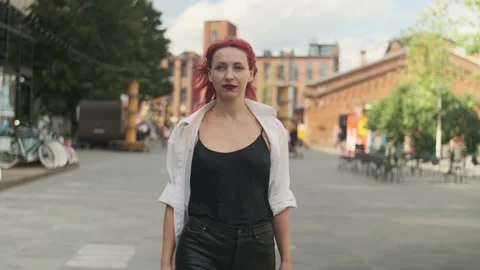 Beautiful well dressed red-haired girl walking along the street Stock Footage 161037424
