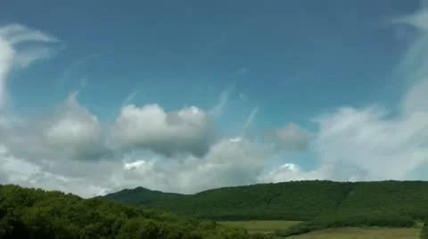 Beautiful white clouds float over green hills and fields. Time lapse Видео 12326373
