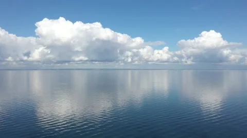 Beautiful white clouds mirroring on the sea with blue sky background Stock Footage 148847490