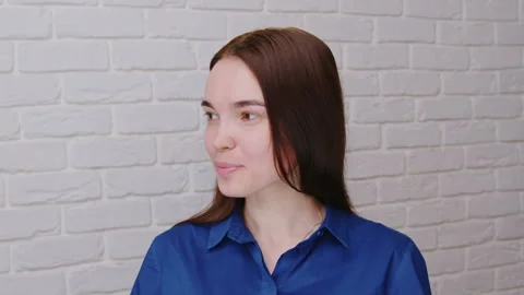 A beautiful white model looks at the camera smiling and straightening her hair Vidéo 332066184
