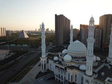 Beautiful white mosque in Central Asia, city center with skyscrapers and park Stock Photos