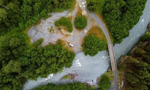 Beautiful wide aerial view of white car near forest river with off-road path Stock Photos