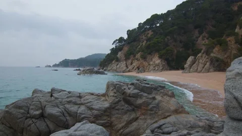 Beautiful wild beach with sand and rocks on a cloudy day, in Spain Stock Footage 230097612