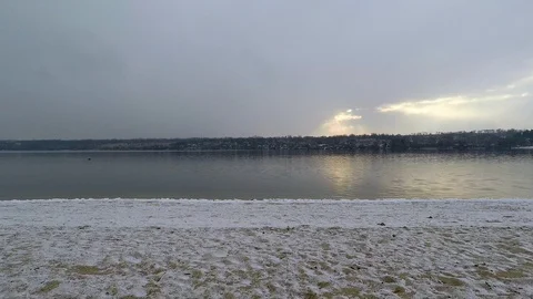 Beautiful winter evening on the sandy beach of the river. snow flakes fall into Stock Footage 100708063