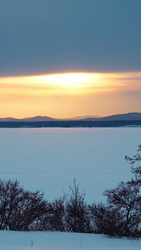 A beautiful winter sunset with a landscape view of the lake and mountains. Vidéo 329637296