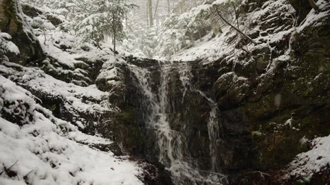 Beautiful winter waterfall flowing through snow forest in mountain Stock Footage 326094487