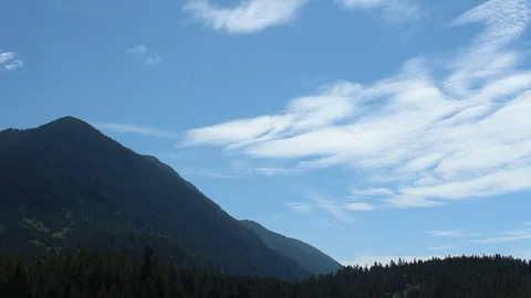 Beautiful Wispy Clouds With A Blue Sky Above Tree Covered Mountains Stock Footage 99940395