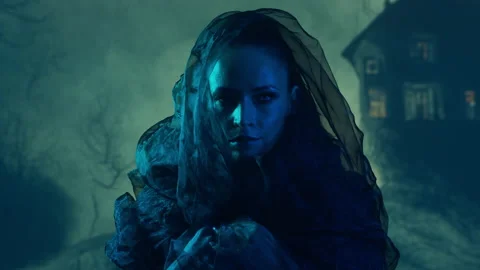 Beautiful witch making the witchcraft over the smoky background. Scary house on Stock Footage 220121388