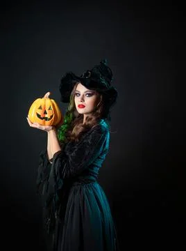 Beautiful witch in a pointed hat Holding a pumpkin with a laughing face, Foto stock