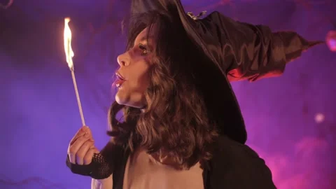 Beautiful witch putting out a match for halloween Stock Footage 163752287