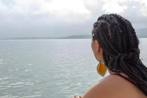 A beautiful woman with african braids hair gazing at the sea Stock Photos