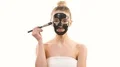 The beautiful woman applying a black face mask on the white background 4k or 4k+ Resolution