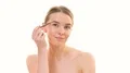 The beautiful woman applying makeup on her face on the white background 4k or 4k+ Resolution