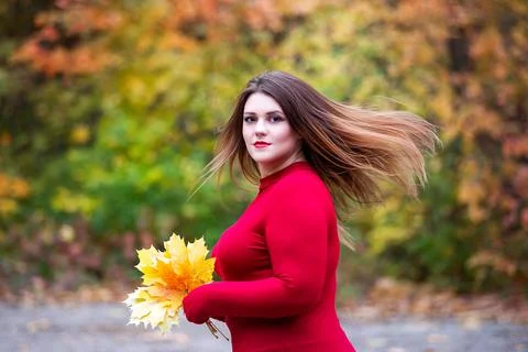 Beautiful woman in autumn, cute plus size model in red sweater outdoors Stock Photos