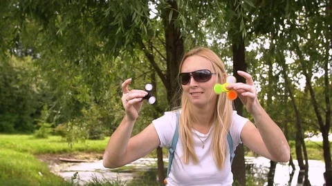 Beautiful woman balancing two fidget spinners on thumbs, slow motion. Stock Footage