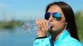 Beautiful woman in blue sports jacket drinks water HD Footage