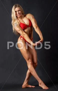 A beautiful woman bodybuilder posing in red bikini and smiling Stock Photos