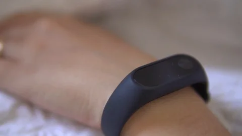 Beautiful woman checking data on her fitness tracker band after waking up in the Stock Footage 91657254